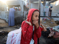 Palestinians survey the damage at the site of an Israeli strike on tents sheltering displaced people at Al-Aqsa Martyrs hospital in Deir Al-...