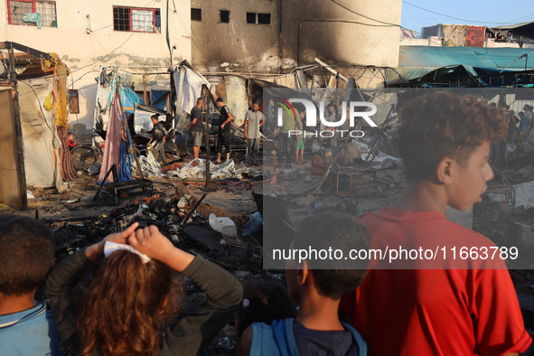 Palestinians survey the damage at the site of an Israeli strike on tents sheltering displaced people at Al-Aqsa Martyrs hospital in Deir Al-...