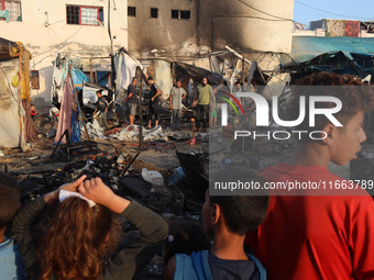 Palestinians survey the damage at the site of an Israeli strike on tents sheltering displaced people at Al-Aqsa Martyrs hospital in Deir Al-...