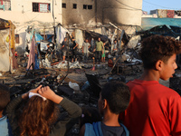 Palestinians survey the damage at the site of an Israeli strike on tents sheltering displaced people at Al-Aqsa Martyrs hospital in Deir Al-...