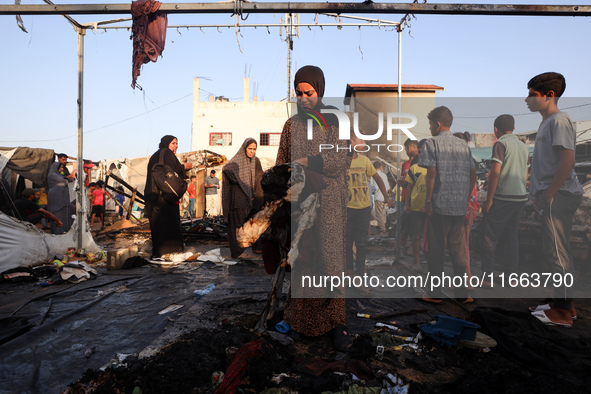 Palestinians survey the damage at the site of an Israeli strike on tents sheltering displaced people at Al-Aqsa Martyrs hospital in Deir Al-...