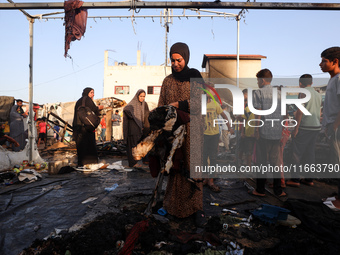 Palestinians survey the damage at the site of an Israeli strike on tents sheltering displaced people at Al-Aqsa Martyrs hospital in Deir Al-...