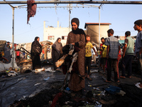 Palestinians survey the damage at the site of an Israeli strike on tents sheltering displaced people at Al-Aqsa Martyrs hospital in Deir Al-...