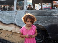 Palestinians survey the damage at the site of an Israeli strike on tents sheltering displaced people at Al-Aqsa Martyrs hospital in Deir Al-...