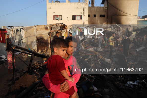 Palestinians survey the damage at the site of an Israeli strike on tents sheltering displaced people at Al-Aqsa Martyrs hospital in Deir Al-...