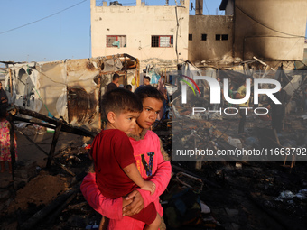 Palestinians survey the damage at the site of an Israeli strike on tents sheltering displaced people at Al-Aqsa Martyrs hospital in Deir Al-...