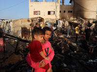 Palestinians survey the damage at the site of an Israeli strike on tents sheltering displaced people at Al-Aqsa Martyrs hospital in Deir Al-...