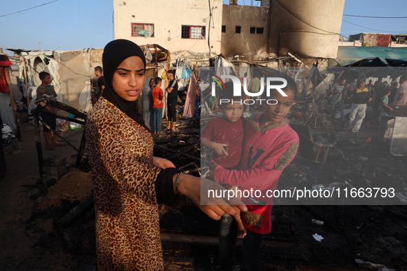 Palestinians survey the damage at the site of an Israeli strike on tents sheltering displaced people at Al-Aqsa Martyrs hospital in Deir Al-...