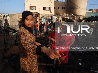 Palestinians survey the damage at the site of an Israeli strike on tents sheltering displaced people at Al-Aqsa Martyrs hospital in Deir Al-...