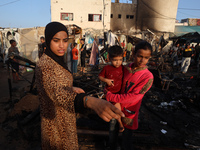 Palestinians survey the damage at the site of an Israeli strike on tents sheltering displaced people at Al-Aqsa Martyrs hospital in Deir Al-...