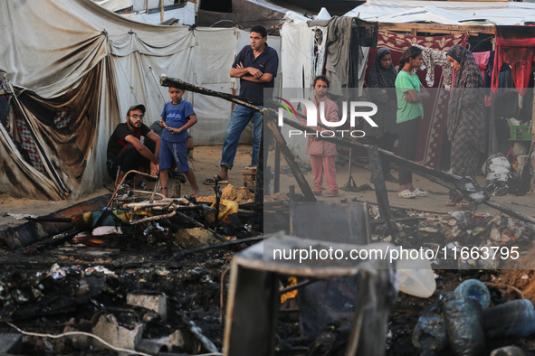 Palestinians survey the damage at the site of an Israeli strike on tents sheltering displaced people at Al-Aqsa Martyrs hospital in Deir Al-...