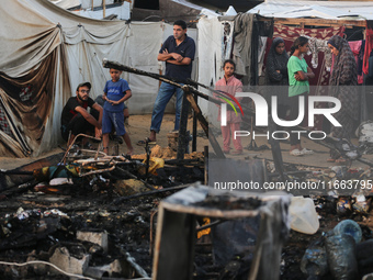 Palestinians survey the damage at the site of an Israeli strike on tents sheltering displaced people at Al-Aqsa Martyrs hospital in Deir Al-...