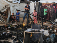 Palestinians survey the damage at the site of an Israeli strike on tents sheltering displaced people at Al-Aqsa Martyrs hospital in Deir Al-...