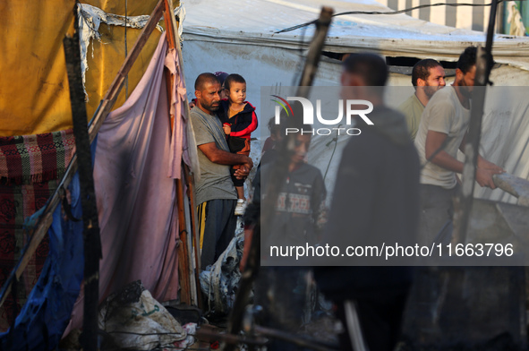 Palestinians survey the damage at the site of an Israeli strike on tents sheltering displaced people at Al-Aqsa Martyrs hospital in Deir Al-...