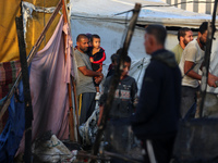 Palestinians survey the damage at the site of an Israeli strike on tents sheltering displaced people at Al-Aqsa Martyrs hospital in Deir Al-...