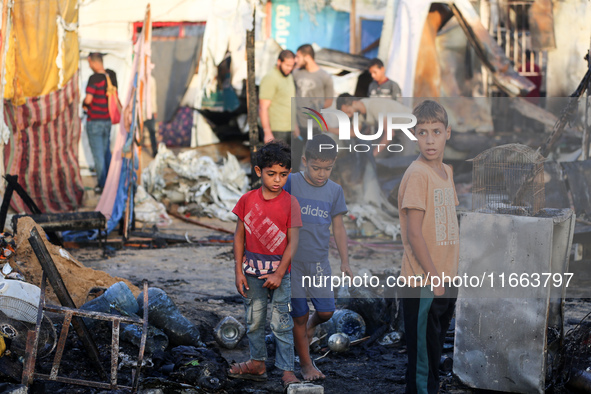 Palestinians survey the damage at the site of an Israeli strike on tents sheltering displaced people at Al-Aqsa Martyrs hospital in Deir Al-...