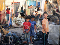 Palestinians survey the damage at the site of an Israeli strike on tents sheltering displaced people at Al-Aqsa Martyrs hospital in Deir Al-...