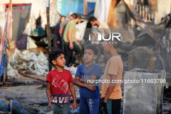 Palestinians survey the damage at the site of an Israeli strike on tents sheltering displaced people at Al-Aqsa Martyrs hospital in Deir Al-...