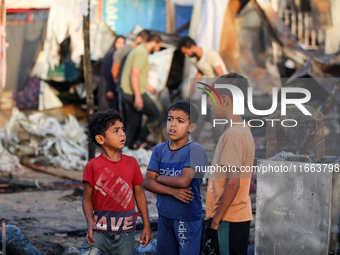 Palestinians survey the damage at the site of an Israeli strike on tents sheltering displaced people at Al-Aqsa Martyrs hospital in Deir Al-...