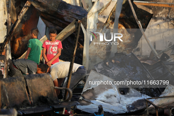 Palestinians survey the damage at the site of an Israeli strike on tents sheltering displaced people at Al-Aqsa Martyrs hospital in Deir Al-...