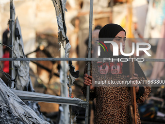 A Palestinian woman observes the site of an Israeli strike on tents sheltering displaced people, amid the Israel-Hamas conflict, at Al-Aqsa...