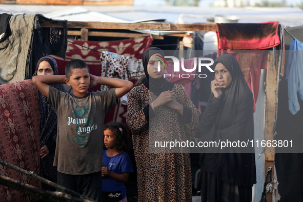 Palestinians survey the damage at the site of an Israeli strike on tents sheltering displaced people at Al-Aqsa Martyrs hospital in Deir Al-...