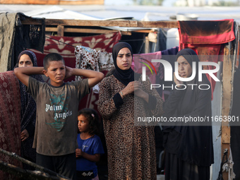 Palestinians survey the damage at the site of an Israeli strike on tents sheltering displaced people at Al-Aqsa Martyrs hospital in Deir Al-...