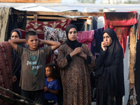 Palestinians survey the damage at the site of an Israeli strike on tents sheltering displaced people at Al-Aqsa Martyrs hospital in Deir Al-...