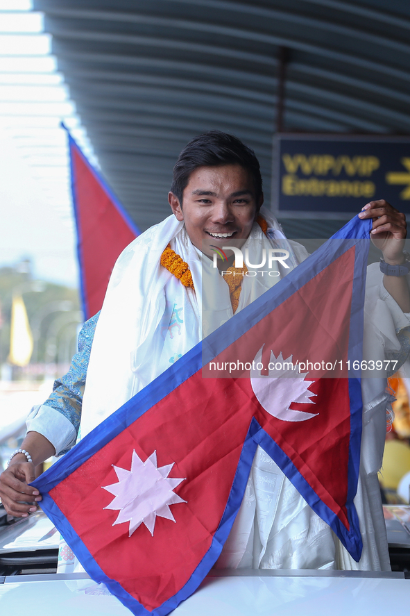 Nepalese youngest record holder climber Nima Rinji Sherpa poses with the national flag for a photo after arriving at Tribhuvan International...