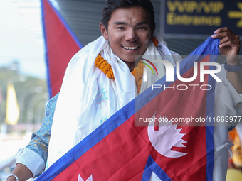 Nepalese youngest record holder climber Nima Rinji Sherpa poses with the national flag for a photo after arriving at Tribhuvan International...