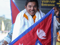 Nepalese youngest record holder climber Nima Rinji Sherpa poses with the national flag for a photo after arriving at Tribhuvan International...