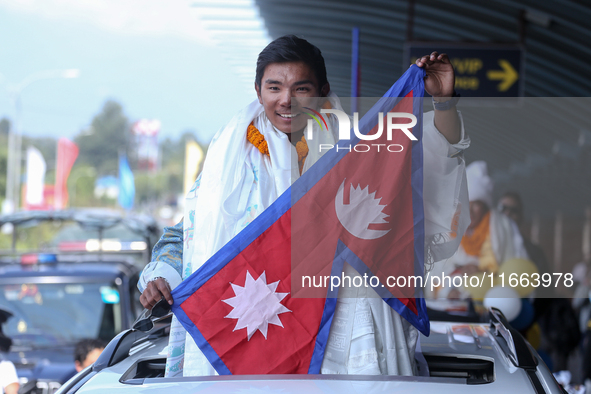 Nepalese youngest record holder climber Nima Rinji Sherpa poses with the national flag for a photo after arriving at Tribhuvan International...