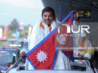 Nepalese youngest record holder climber Nima Rinji Sherpa poses with the national flag for a photo after arriving at Tribhuvan International...