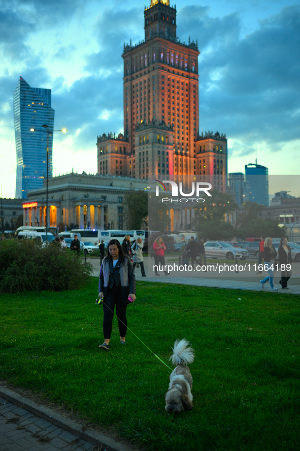 A woman walks a dog in front of the Palace of Culture and Sciences in Warsaw, Poland on 12 October, 2024. 