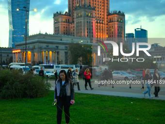 A woman walks a dog in front of the Palace of Culture and Sciences in Warsaw, Poland on 12 October, 2024. (