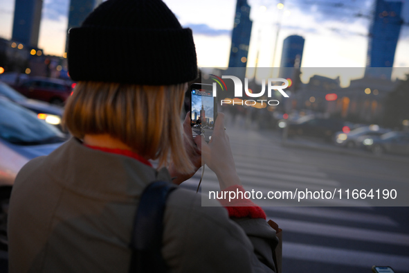 A woman takes a photo of the Palace of Culture and Sciences with her mobile phone in Warsaw, Poland on 12 October, 2024. 