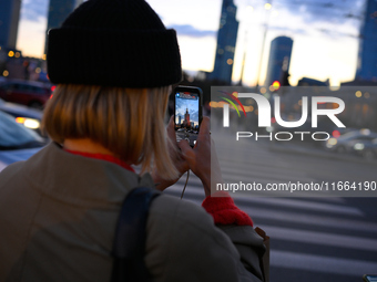 A woman takes a photo of the Palace of Culture and Sciences with her mobile phone in Warsaw, Poland on 12 October, 2024. (