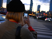 A woman takes a photo of the Palace of Culture and Sciences with her mobile phone in Warsaw, Poland on 12 October, 2024. (