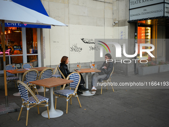 Two young woman are seen having drinks sitting outdoors at a cafe in Warsaw, Poland on 12 October, 2024. (