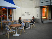 Two young woman are seen having drinks sitting outdoors at a cafe in Warsaw, Poland on 12 October, 2024. (