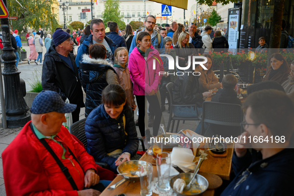 People are seen waiting in line at a restaurant in Warsaw, Poland on 12 October, 2024. 