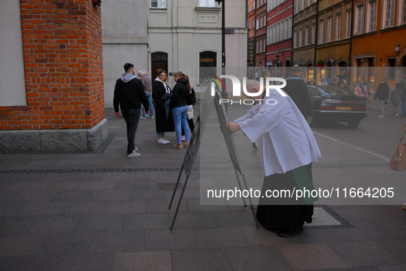 A clergyman sets up a sign outside a church in Warsaw, Poland on 12 October, 2024. 