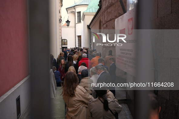 People wait in line in a small alley beside a church during a wedding ceremony in Warsaw, Poland on 12 October, 2024. 