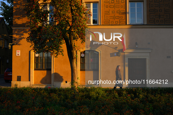 A woman walks past a house in the Old Town during sunset in Warsaw, Poland on 12 October, 2024. 