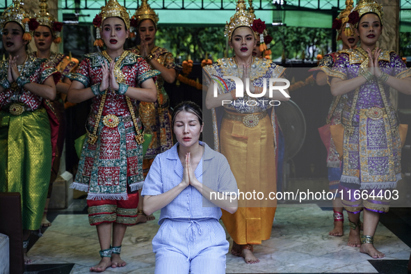 Devotees pray as dancers perform while worshiping Lord Brahma, the Hindu god of creation, for good fortune at the Erawan Shrine in Bangkok,...