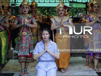 Devotees pray as dancers perform while worshiping Lord Brahma, the Hindu god of creation, for good fortune at the Erawan Shrine in Bangkok,...