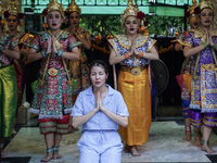 Devotees pray as dancers perform while worshiping Lord Brahma, the Hindu god of creation, for good fortune at the Erawan Shrine in Bangkok,...