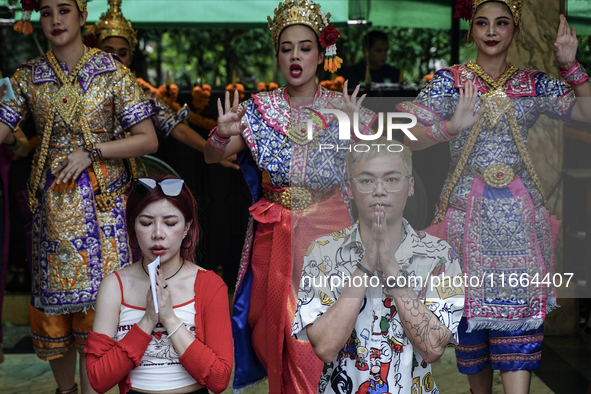 Devotees pray as dancers perform while worshiping Lord Brahma, the Hindu god of creation, for good fortune at the Erawan Shrine in Bangkok,...