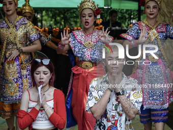 Devotees pray as dancers perform while worshiping Lord Brahma, the Hindu god of creation, for good fortune at the Erawan Shrine in Bangkok,...