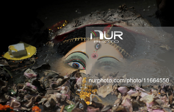 An idol of Goddess Durga is seen in the waters of the Kuakhai River as devotees immerse it, marking the conclusion of the 10-day Durga Puja...